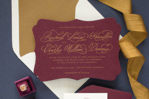 gold and burgundy wedding invitation with calligraphy