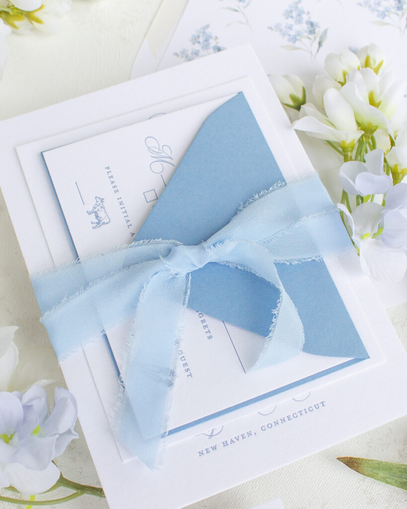 frayed edge silk ribbon tied around a wedding invitation